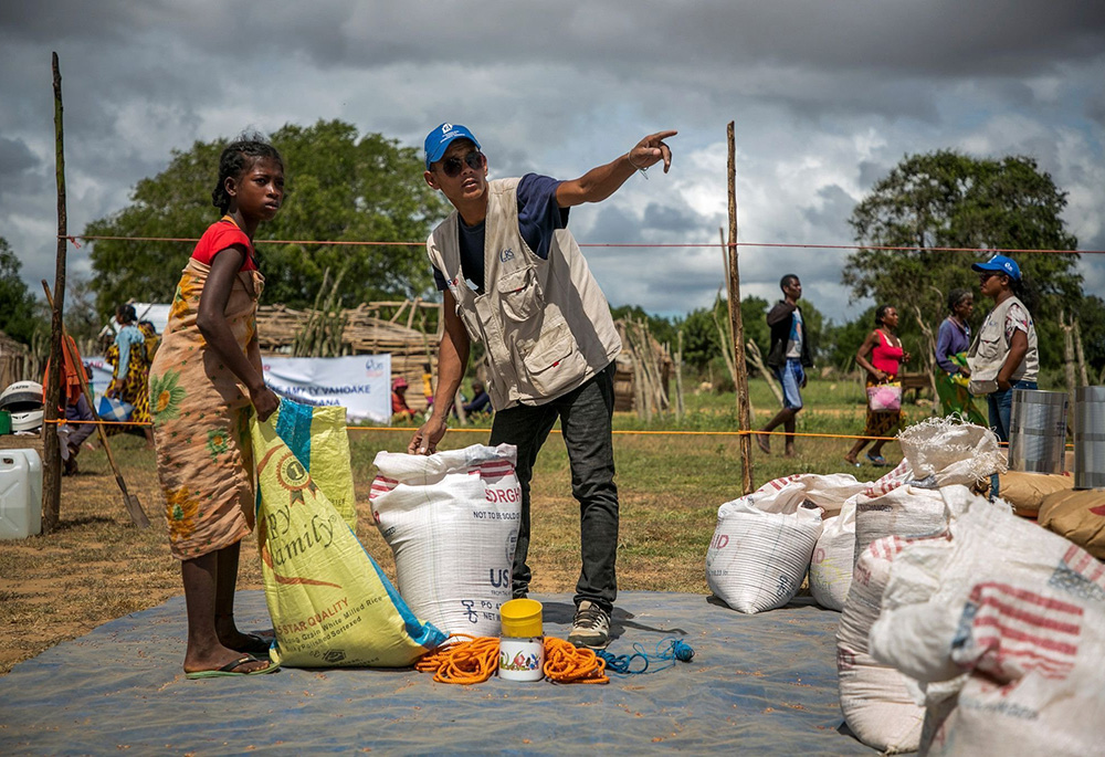 A Catholic Relief Services worker is helping a young woman at a food distribution area in Marojela village, located in the Marolinta commune in southern Madagascar's Beloha District. On this day, 416 people from six villages received food. Over the past several years, the southern region of Madagascar has been affected by recurring droughts. (OSV News/Courtesy of Catholic Relief Services/Jim Stipe)